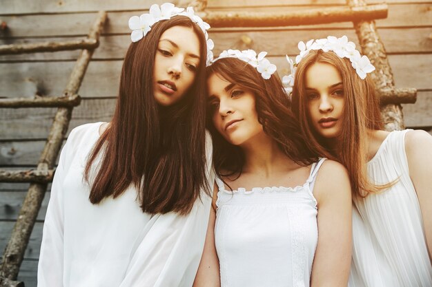 Free photo relaxed young women with white clothes and floral wreath