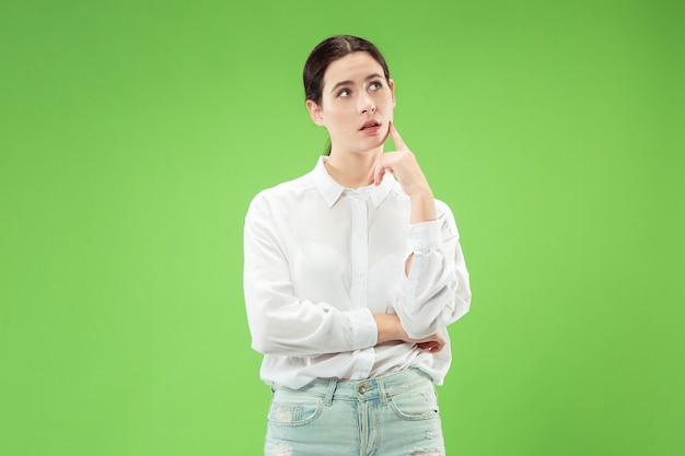 Remember all. Let me think. Doubt concept. Doubtful, thoughtful woman remembering something. Young emotional woman. Human emotions, facial expression concept. Studio. Isolated on trendy green