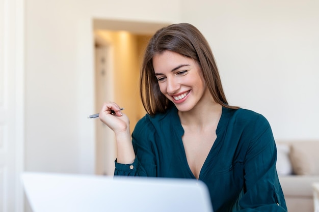 Remote job technology and people concept happy smiling young business woman with laptop computer and papers working at home office