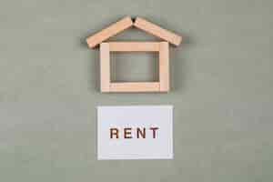 Free photo renting house concept with wooden blocks, sticky note on grey background flat lay.