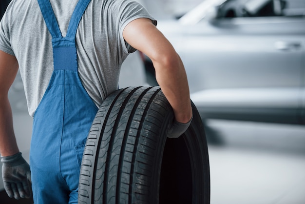 Free photo repair concept. mechanic holding a tire at the repair garage. replacement of winter and summer tires