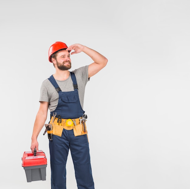 Free photo repairman in blue overall with tool box looking away