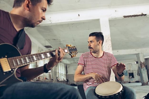 Free Photo repetition of rock music band. electric guitar player and drummer behind the drum set.