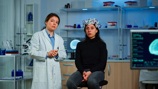 Researcher and patient with eeg headset looking at virtual display with touchscreen, virtual reality using medical inovation in neurological research lab. Scientists working with healthcare simulator