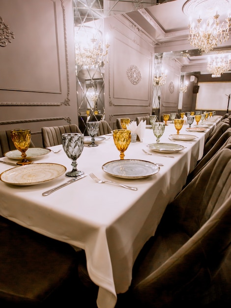 Free photo restaurant dinner table with plates cutlery yellow and blue glasses