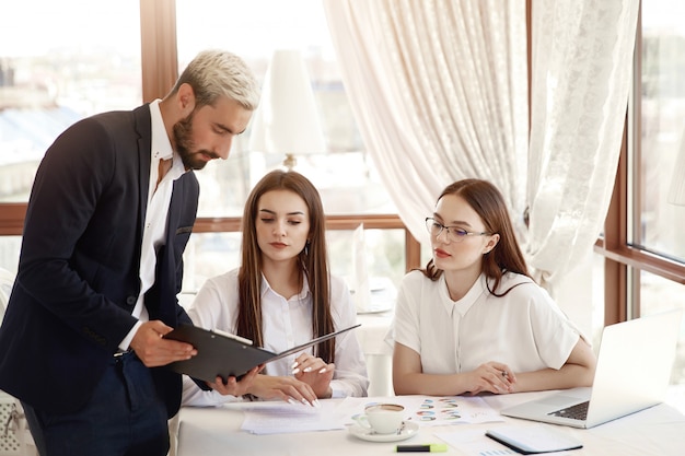 Free Photo restaurant director is showing financial diagrams in the documents and two assistants women are listening with attention