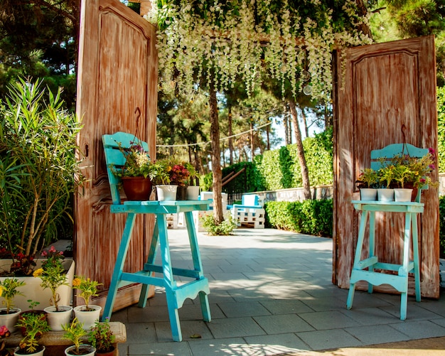 Free photo restaurant entrance with wood doors and two turquoise chairs with plant