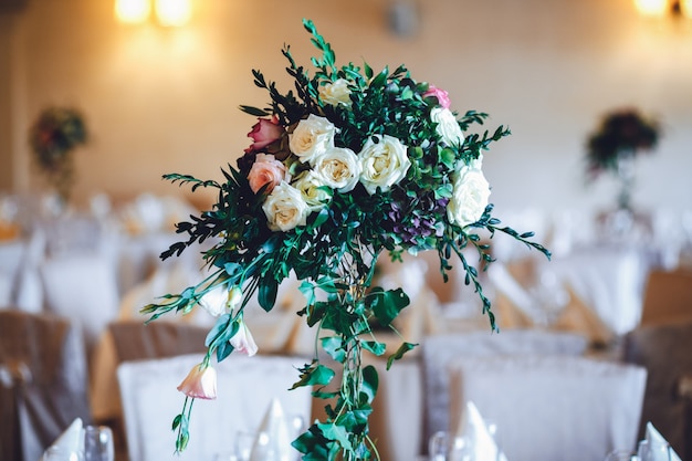 Restaurant hall with tables decorated with tall vases with roses