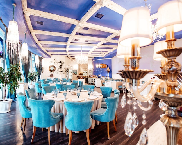 Restaurant hall with turquoise chairs, navy coloured ceiling, classic chandeliers and white walls