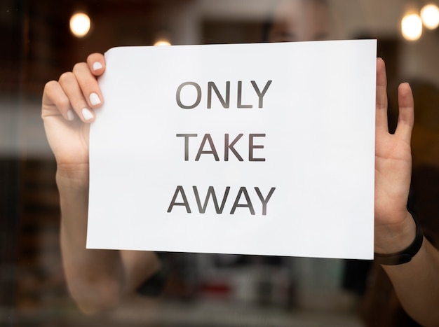 Free photo restaurant worker putting a takeaway sign in front o the restaurant