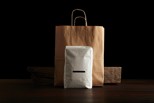 Retailer merchandise pack: big hermetic pouch white with blank label presented in front of craft paper bag and rustic wooden brick on red table