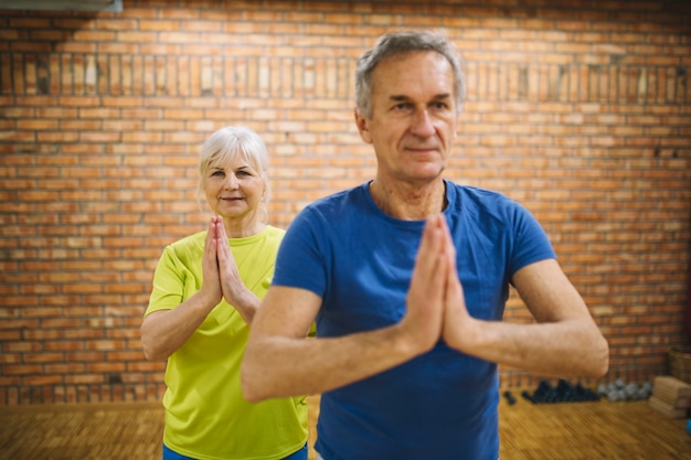 Retired couple meditating in gym