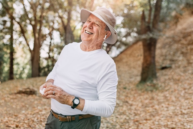 Free photo retired man enjoying music in the middle of the forest