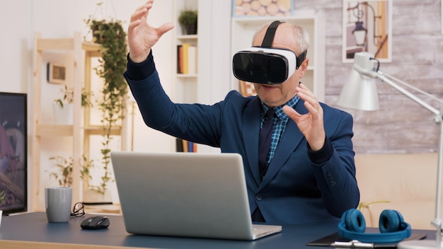 Free photo retired man experiencing virtual reality using vr headset in living room. cup of coffee on the table.