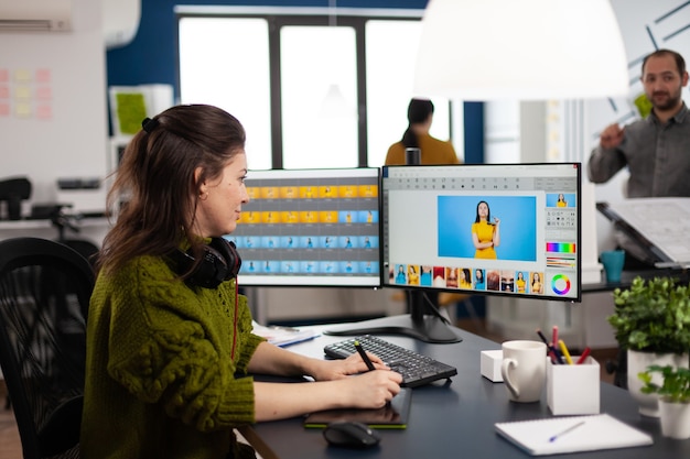 Retoucher woman editor working on computer with two monitors and stylus