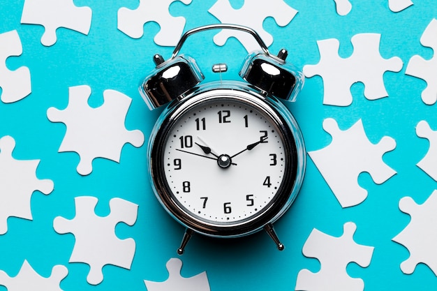 Free Photo retro alarm clock and jigsaw puzzle pieces on blue backdrop