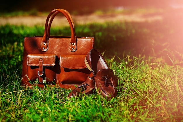 Retro brown shoes and man leather bag in bright colorful summer grass in the park