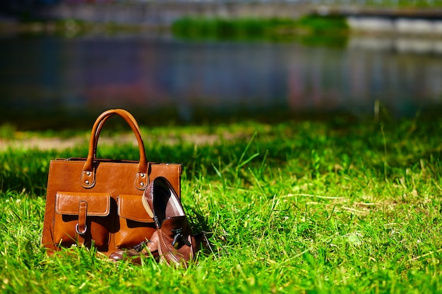 Retro brown shoes and man leather bag in bright colorful summer grass in the park