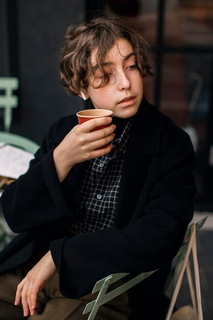 Retro looking non binary person enjoying a coffee