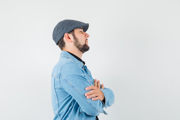 Retro-style man standing with crossed arms in jacket,cap .