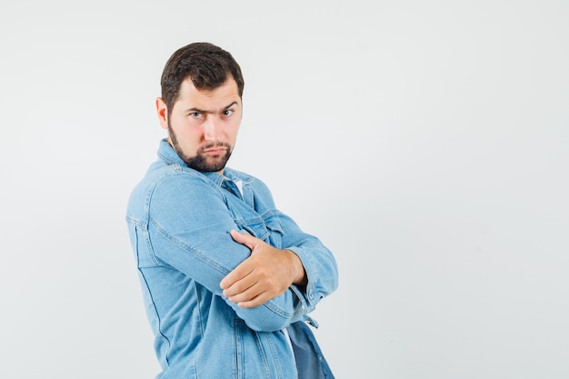 Retro-style man standing with crossed arms in jacket,t-shirt and looking serious , front view.