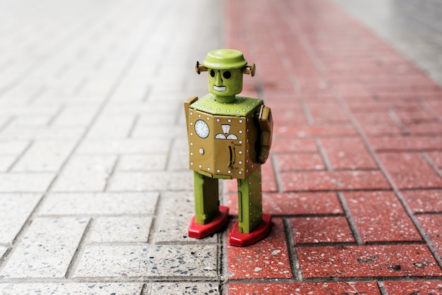 Free Photo retro tin robot toy standing on ground with pattern