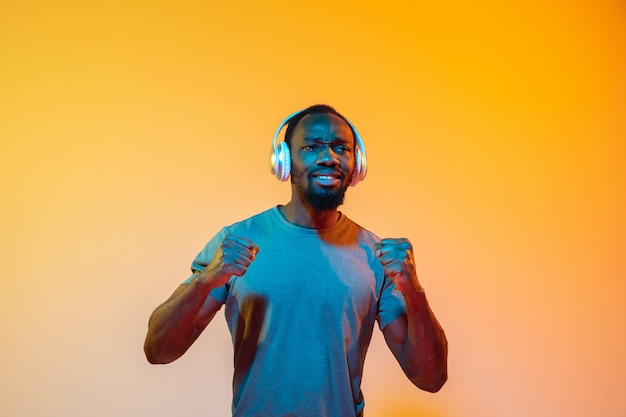 The retro wave or synth wave portrait of a young happy serious african man at studio.