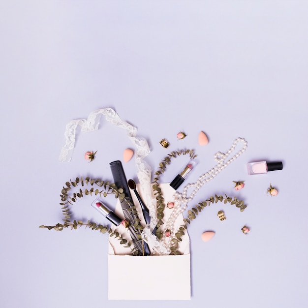 Ribbon; lipstick; comb; necklace with twig and flowers coming out from envelope