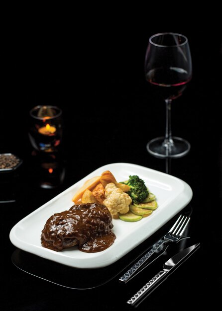 Ribeye steak in teriyaki sauce with glass of burgundy