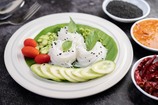 Rice noodles in a banana leaf with beautifully laid vegetables and side dishes. Thai food.