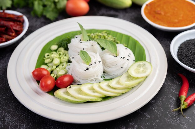 Rice noodles in a banana leaf with beautifully laid vegetables and side dishes. Thai food.