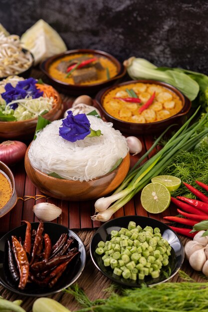 Rice noodles in a bowl of curry paste with chili, cucumber, long bean, lime, garlic and spring onion