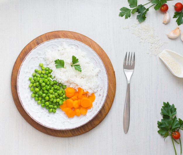 Free Photo rice with vegetables on wooden board near fork and garlic