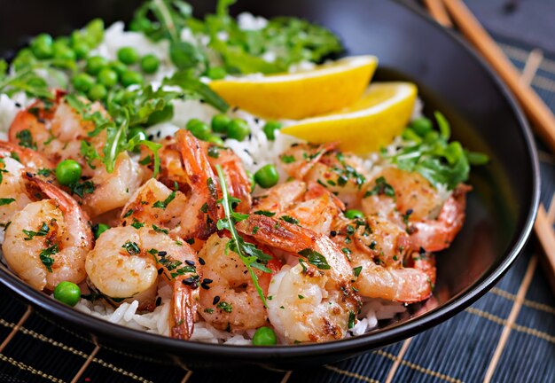 Rice with young green peas, shrimps and arugula in black bowl. Healthy food. Buddha bowl