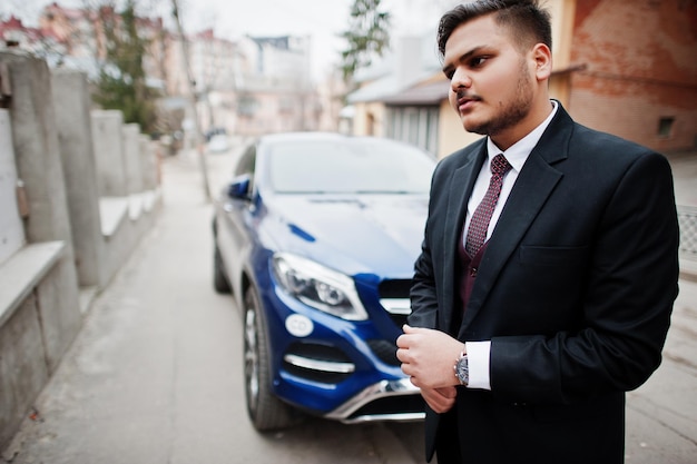 Free Photo rich indian diplomat businessman in formal wear standing against business suv car