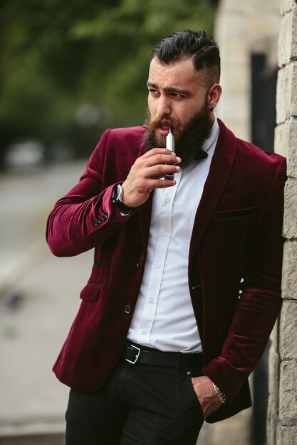 A rich man with a beard smokes electronic cigarette