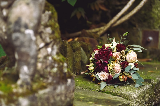 Free photo rich red autumn wedding bouquet lies on the stone footsteps