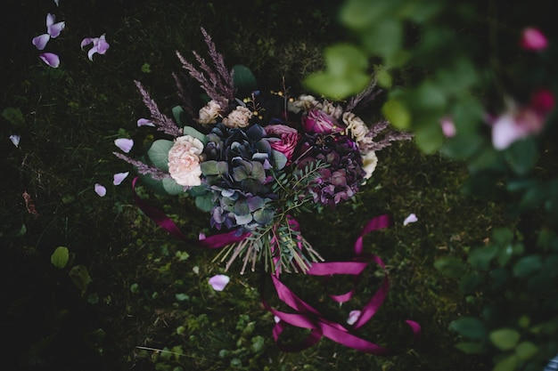 Free Photo rich wedding bouquet made of dark flowers and greenery lies on the green lawn