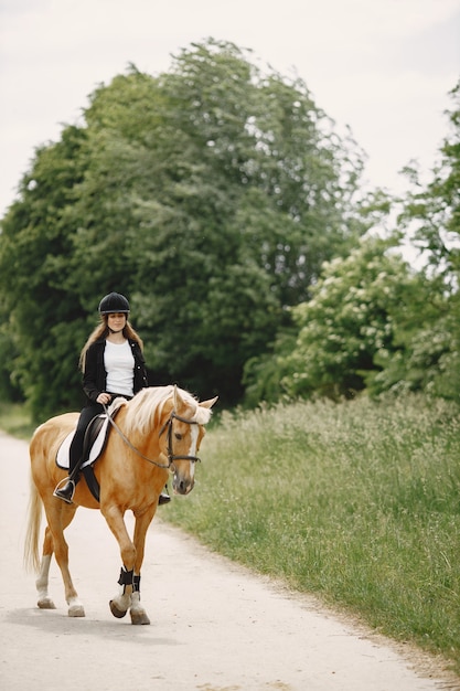 Free photo rider woman riding her horse on a ranch. woman has long hair and black clothes. female equestrian on her brown horse.