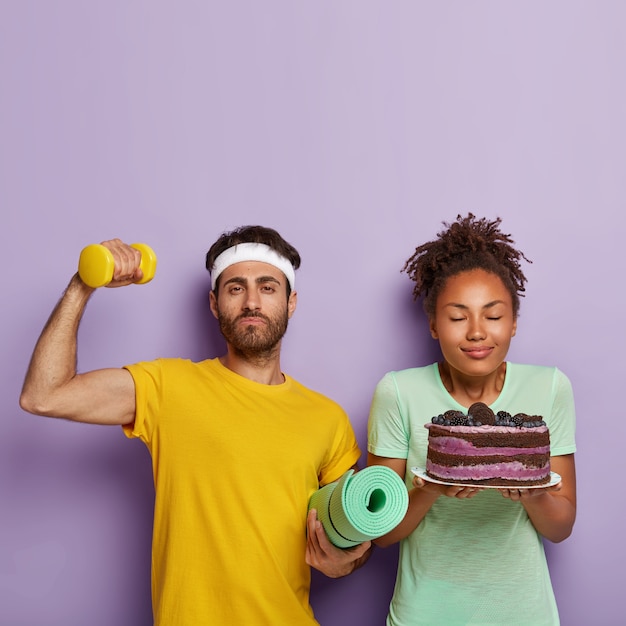 Right choice concept. Strong muscular man in yellow t shirt, raises hand with dumbbell, being for healthy lifestyle