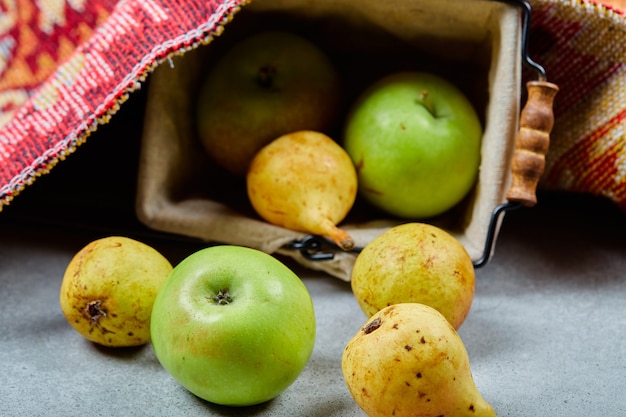 Free Photo ripe apples and pears in basket and on white surface.