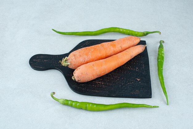 Ripe carrots and peppers on dark board.