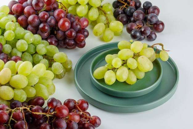 Free photo ripe grapes in a saucer with plate high angle view on a white