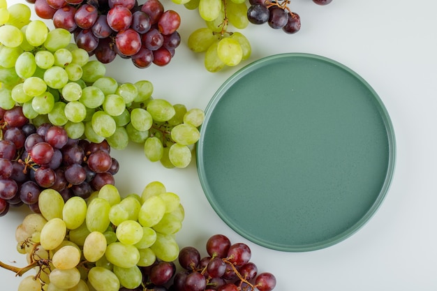 Ripe grapes with empty tray flat lay on a white