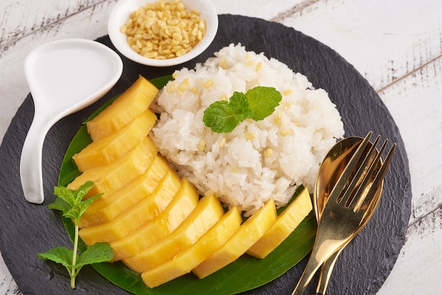 Ripe mango and sticky rice with coconut milk on stone surface, Thai sweet dessert on summer season.