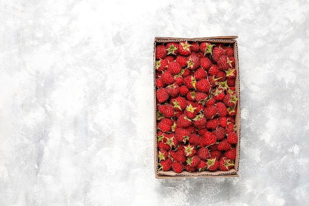 Free photo ripe sweet raspberries in box on grey concrete . close up, top view