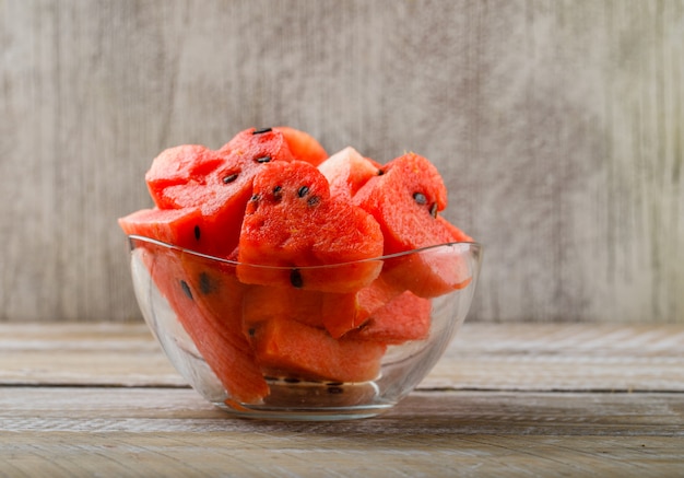 Free photo ripe watermelon pieces in a glass bowl on wooden and grunge background. side view.