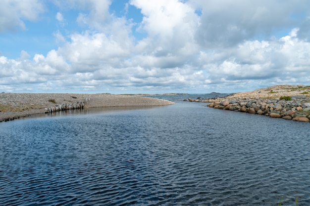 River surrounded by rocks under the sunlight and a cloudy sky at daytime