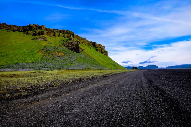 Free photo road near a grassy mountain under a blue sky