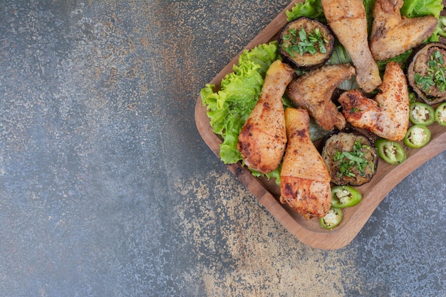 Free photo roasted chicken legs and wings on wooden board with lettuce and pepper. high quality photo